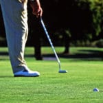 A golfer potting the ball into the hole